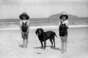 Little children at a beach with a dog, circa 1930s.
