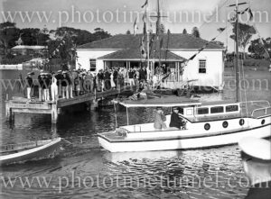 Season opening for Lake Macquarie Yacht Club, October 19, 1935. Scene shows clubhouse and crowd on jetty.